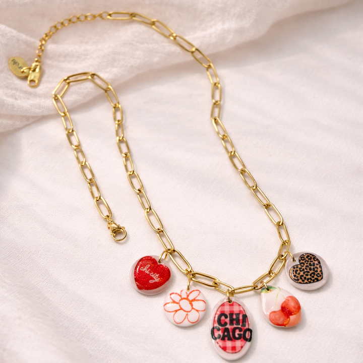 Gold chain necklace with colorful charms on a light fabric background