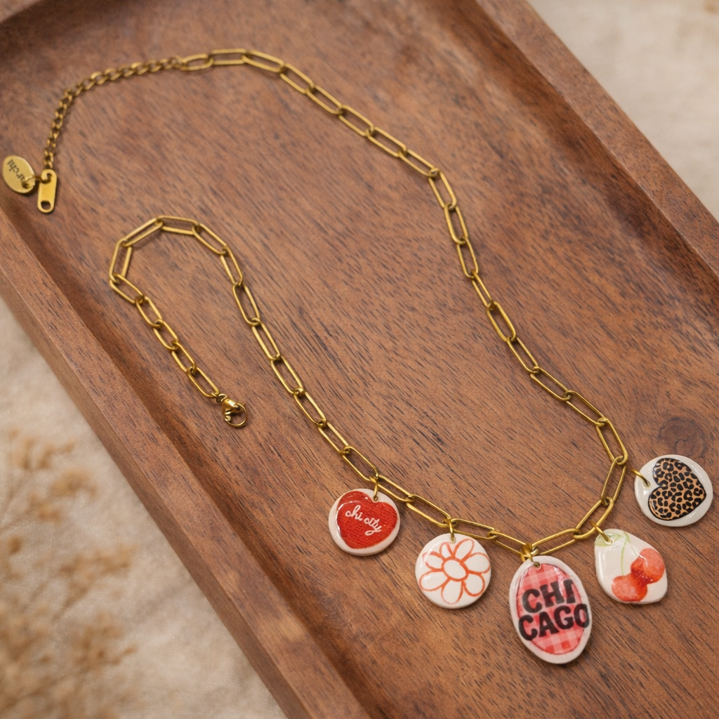 Gold necklace with colorful charms on a wooden tray