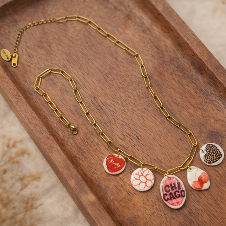 Gold necklace with colorful charms on a wooden tray