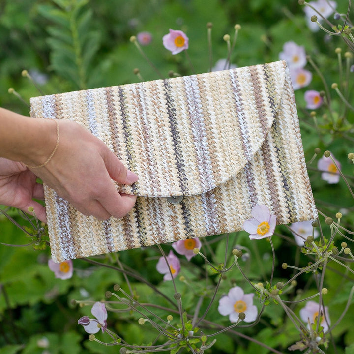 Model holding the Emilia clutch, highlighting its size and stylish stripe pattern.