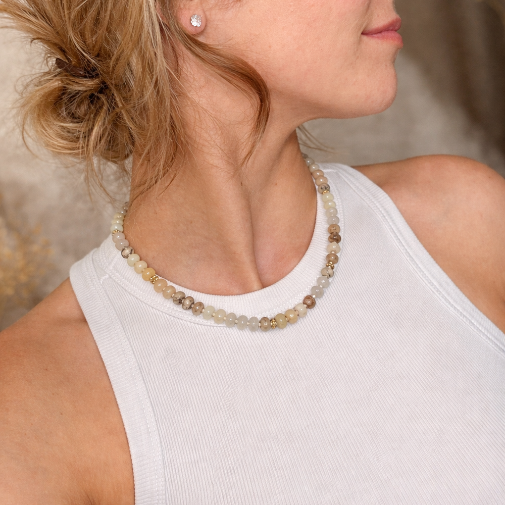 Woman wearing a beaded necklace and earring against a neutral background