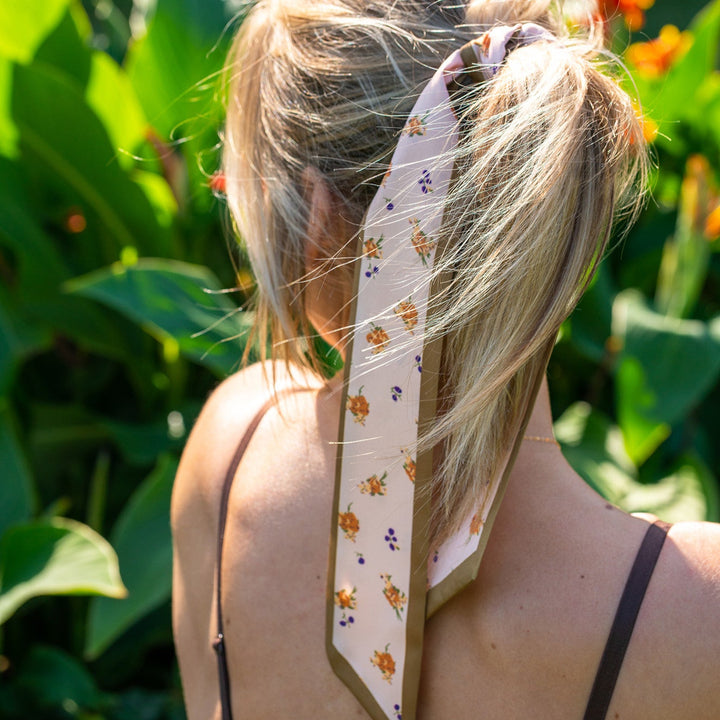 Light tan satin scarf with floral designs in orange, yellow, purple, and green.
