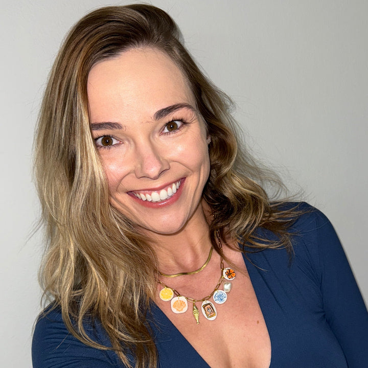 Woman wearing a blue top with a necklace against a plain background