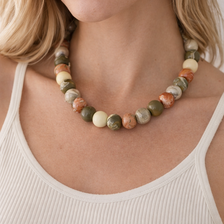 Close-up of a woman wearing a beaded necklace with a neutral background
