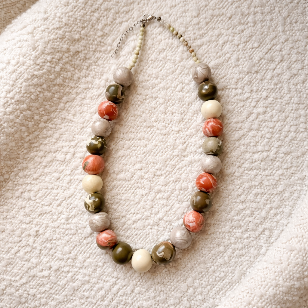 Necklace with multicolored beads on a textured beige surface